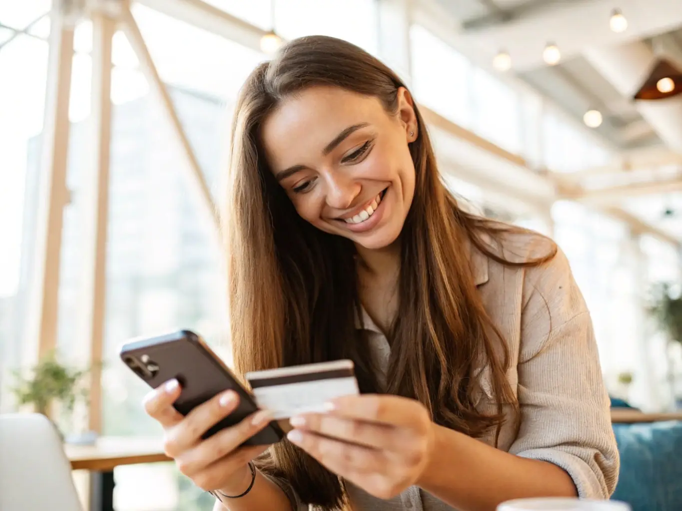 A person happily using a Mercury credit card to make a purchase at a modern cafe, showcasing the convenience and lifestyle benefits of the card.